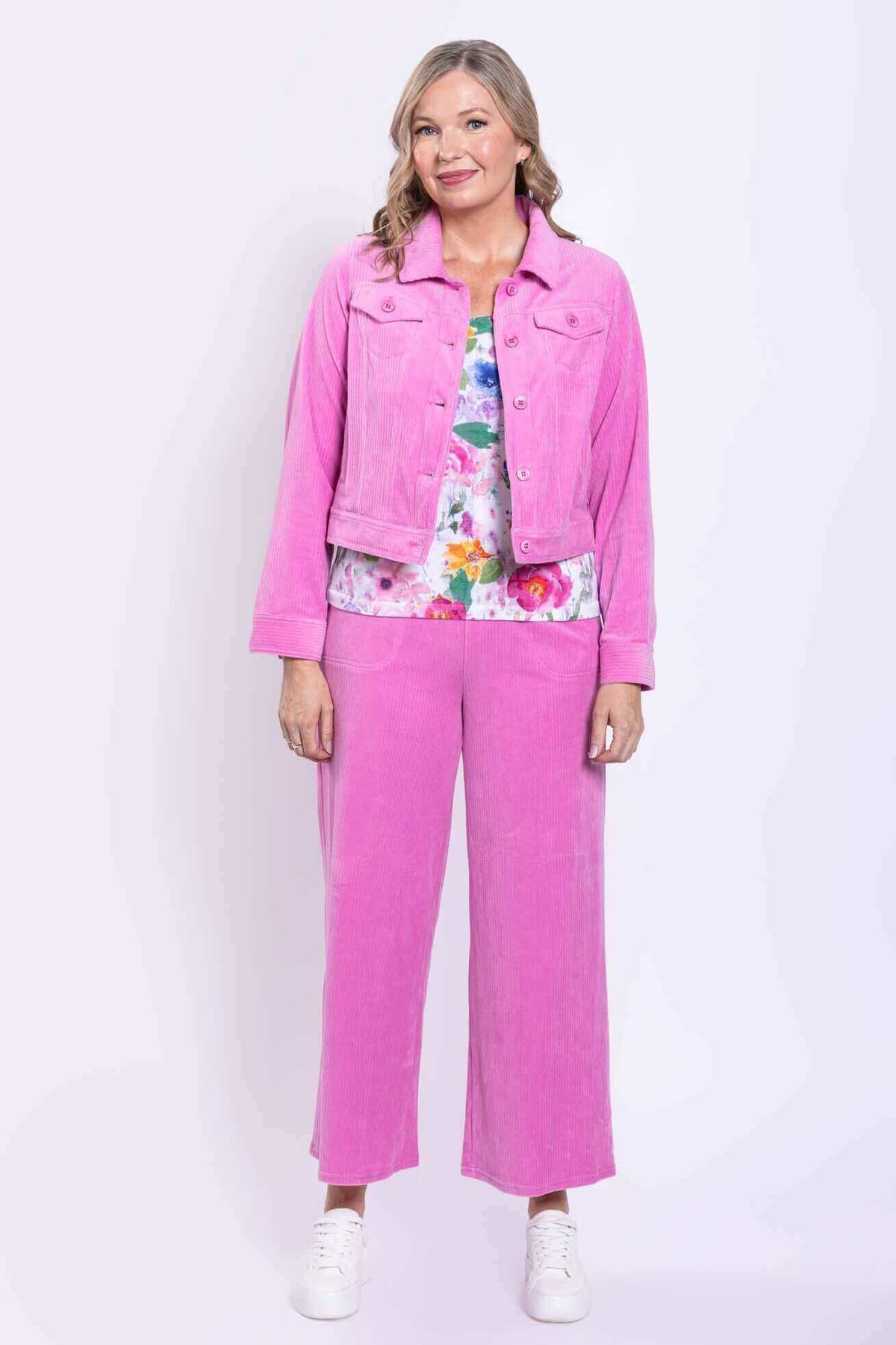 Full front view of woman in pink corduroy jacket and pants with floral shirt