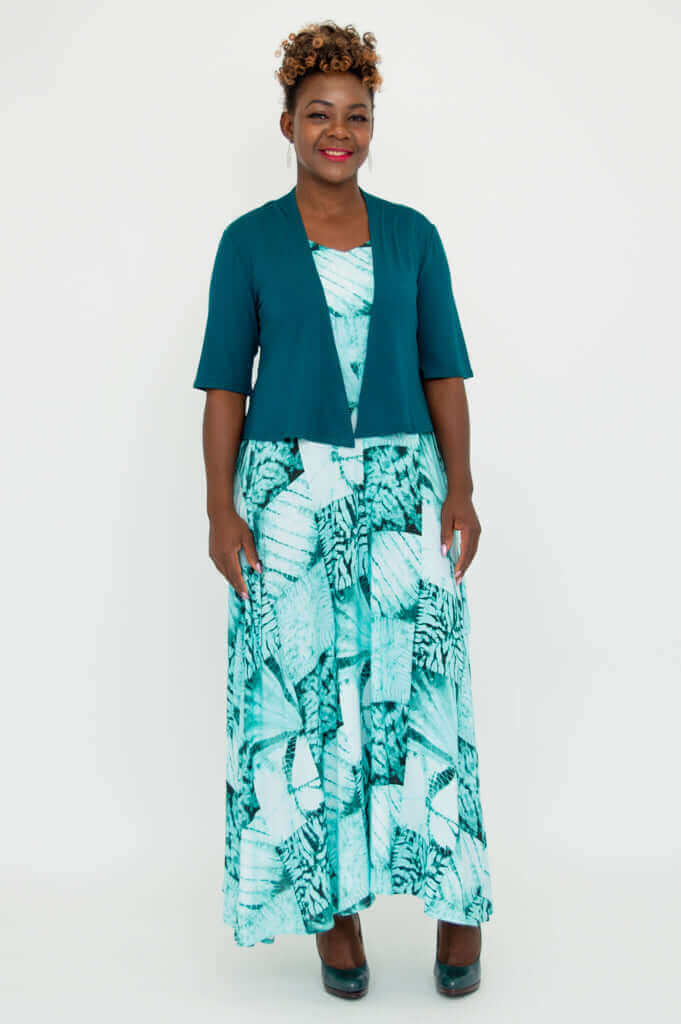 Full body front view of woman in teal Doda Jacket and green patterned maxi dress