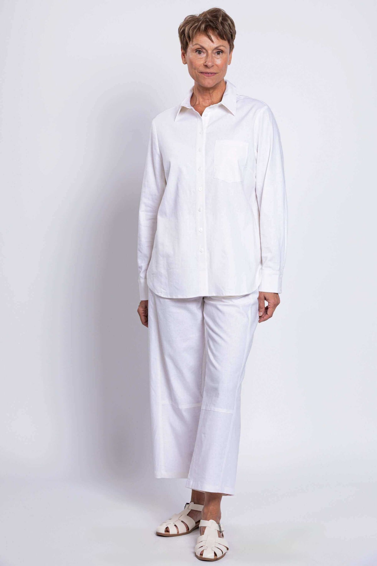 Full body front view of a woman in a white relaxed shirt and matching pants