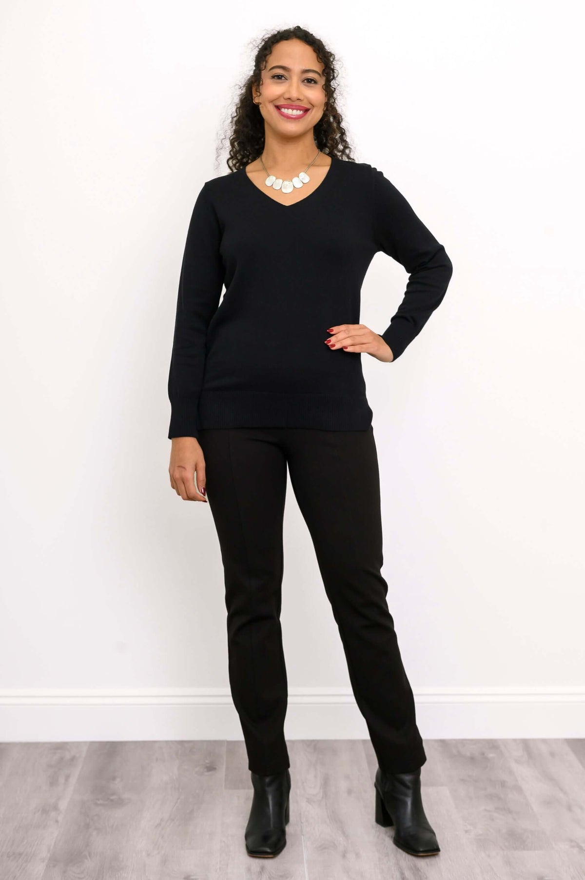 Full body front view of woman modeling a black V-neck cotton sweater with boots