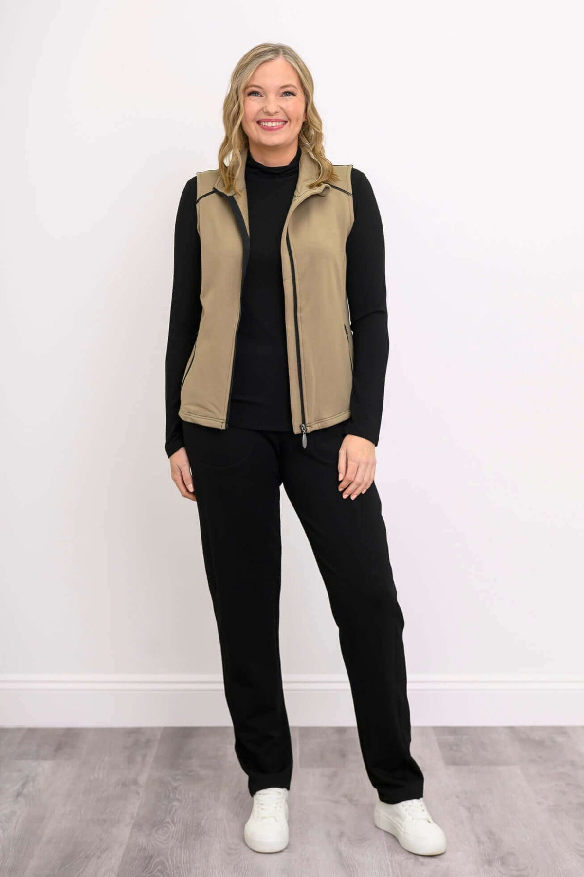 Full body front view of woman wearing tan Hartford Utility Vest and black pants