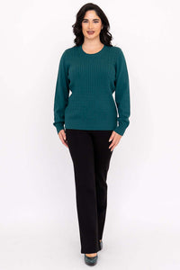 Full body front view of a woman in a teal crew neck cable knit sweater and black pants