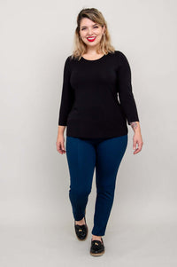 Model walking in a black 3/4 sleeve tee and blue pants, full body front view