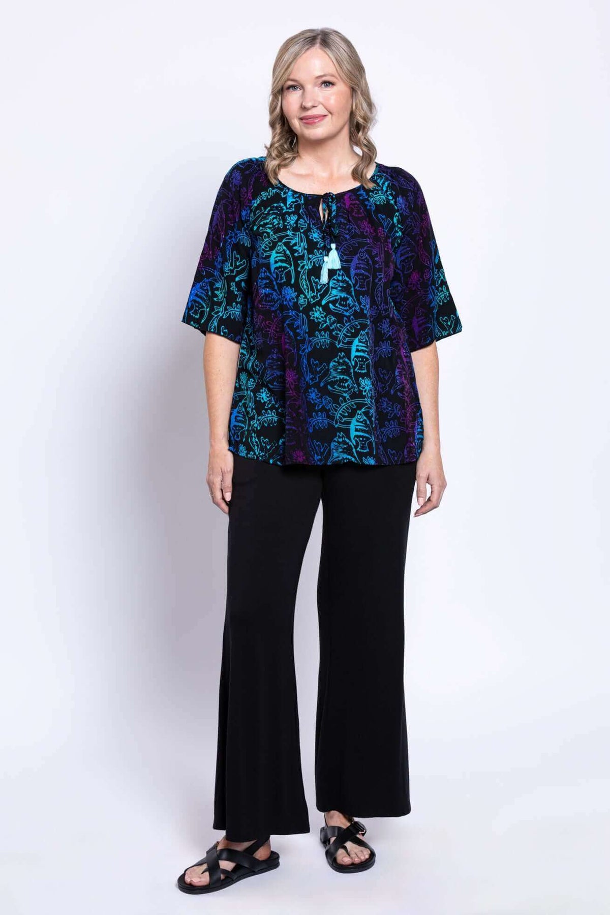 Full body view of a woman in a Luna Boho Peasant Top and black wide-leg pants