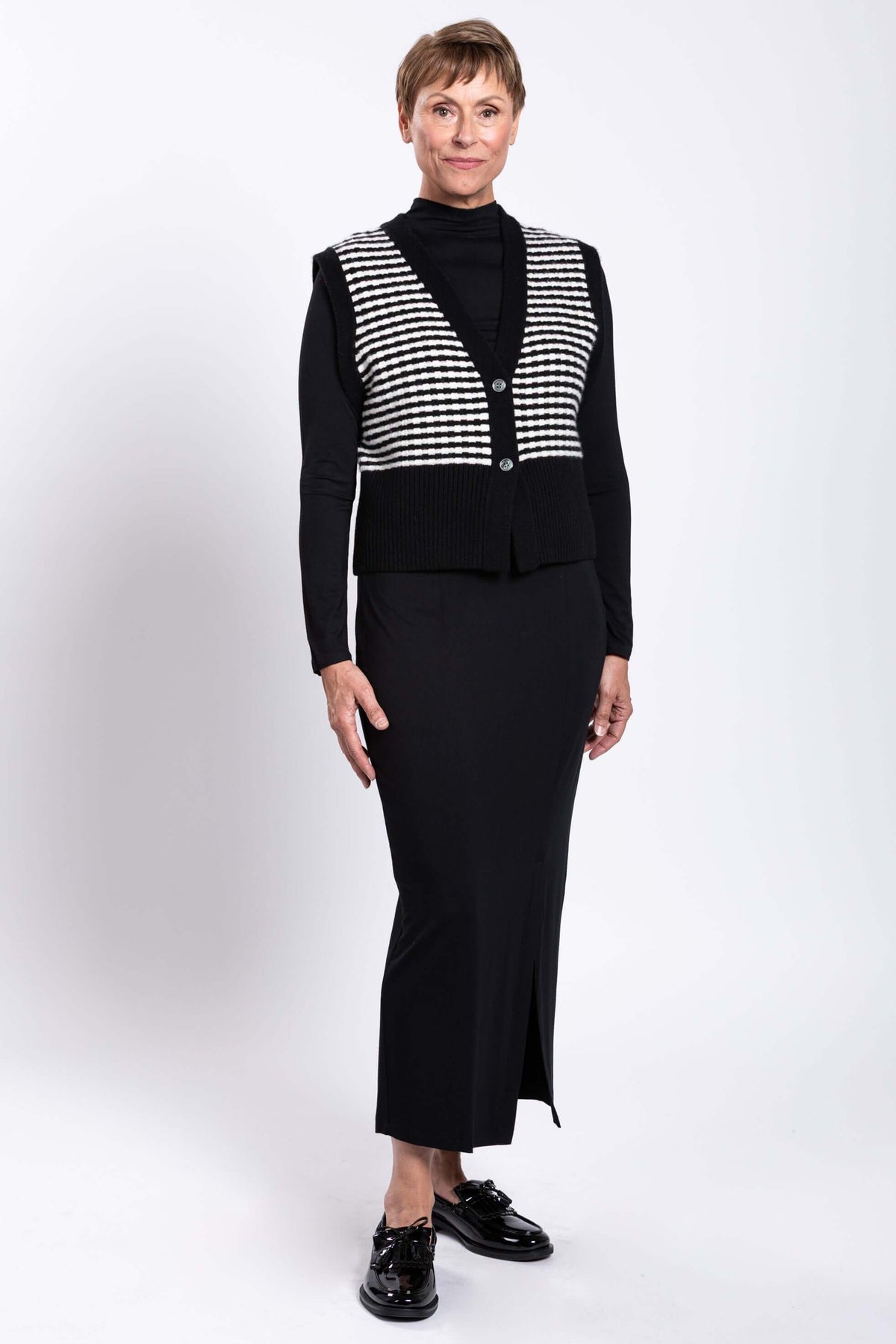 Full body image of a woman in a striped vest and black maxi skirt