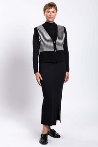 Full body image of a woman in a striped vest and black maxi skirt