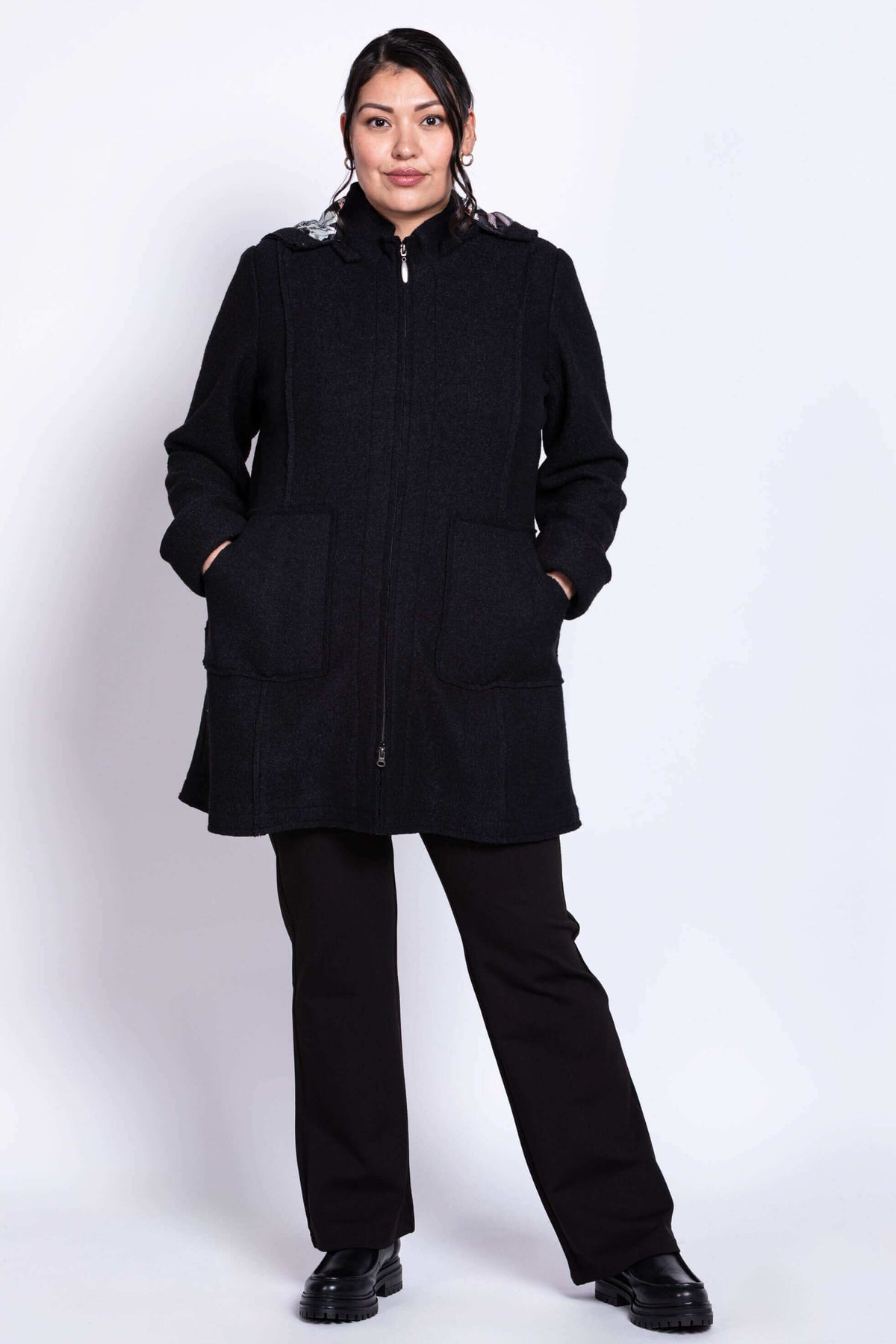 Full body view of model in black boiled wool car coat and trousers