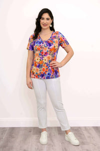 Full view of woman in vibrant floral bamboo top and white pants