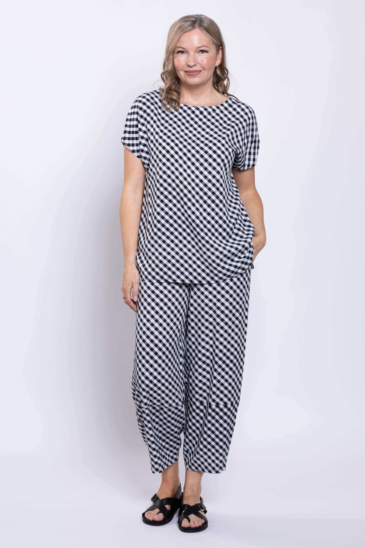 Full body view of woman in matching black and white gingham top and wide-leg pants