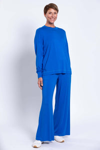 Full body view of woman wearing blue crew neck top and wide-leg matching pants