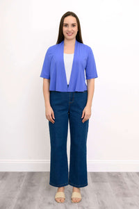 Full body view of model in blue cropped short sleeve jacket with jeans