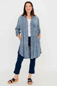 Full body shot of a woman standing in a blue striped oversized shirt tunic and navy pants