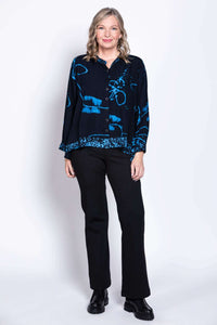 Full body view of woman in blue Batik high-low blouse with black pants