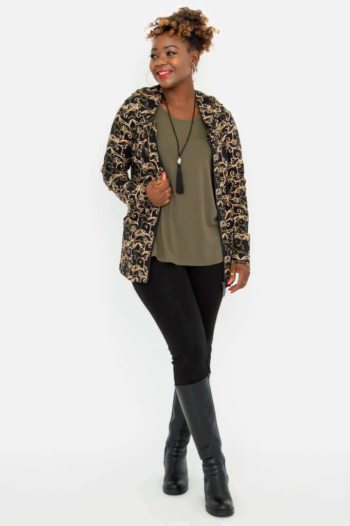 Woman modeling a hooded jacket with vine print, open over an olive top, full body view