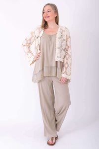 Full body shot of woman modeling a cream crochet cardigan, wide-leg pants, and sandals