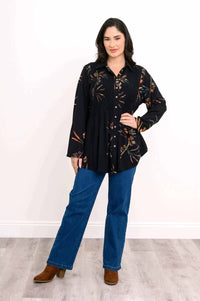 Full body view of a woman modeling a black tunic with smocking and floral accents