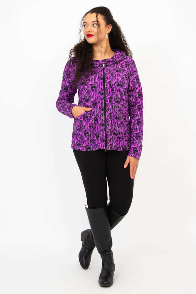 Full body view of woman modeling a purple patterned hoodie and black pants