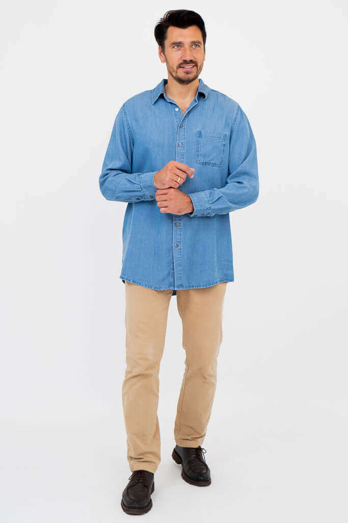 Full body view of man in light blue button-up shirt, tan pants and black shoes