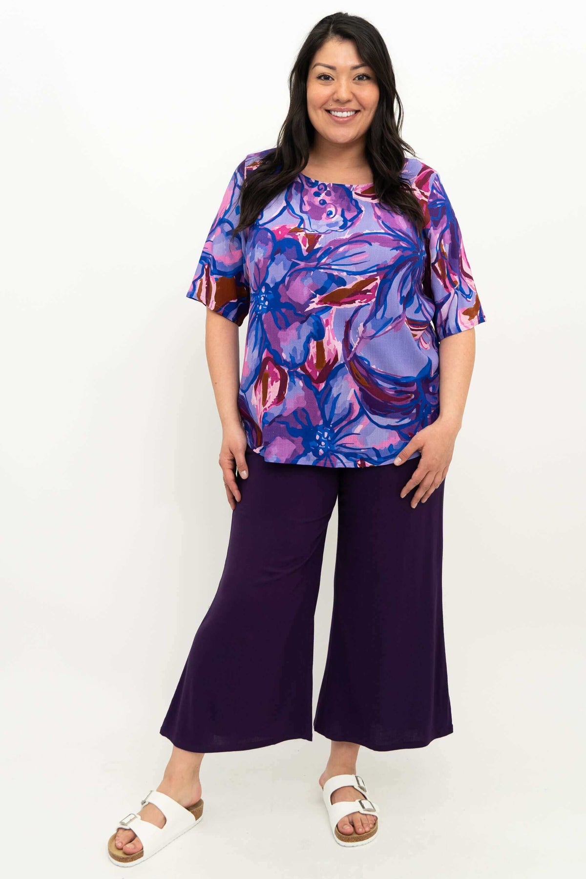 Full body view of a woman modeling the Liza Water Iris floral blouse with wide-leg pants