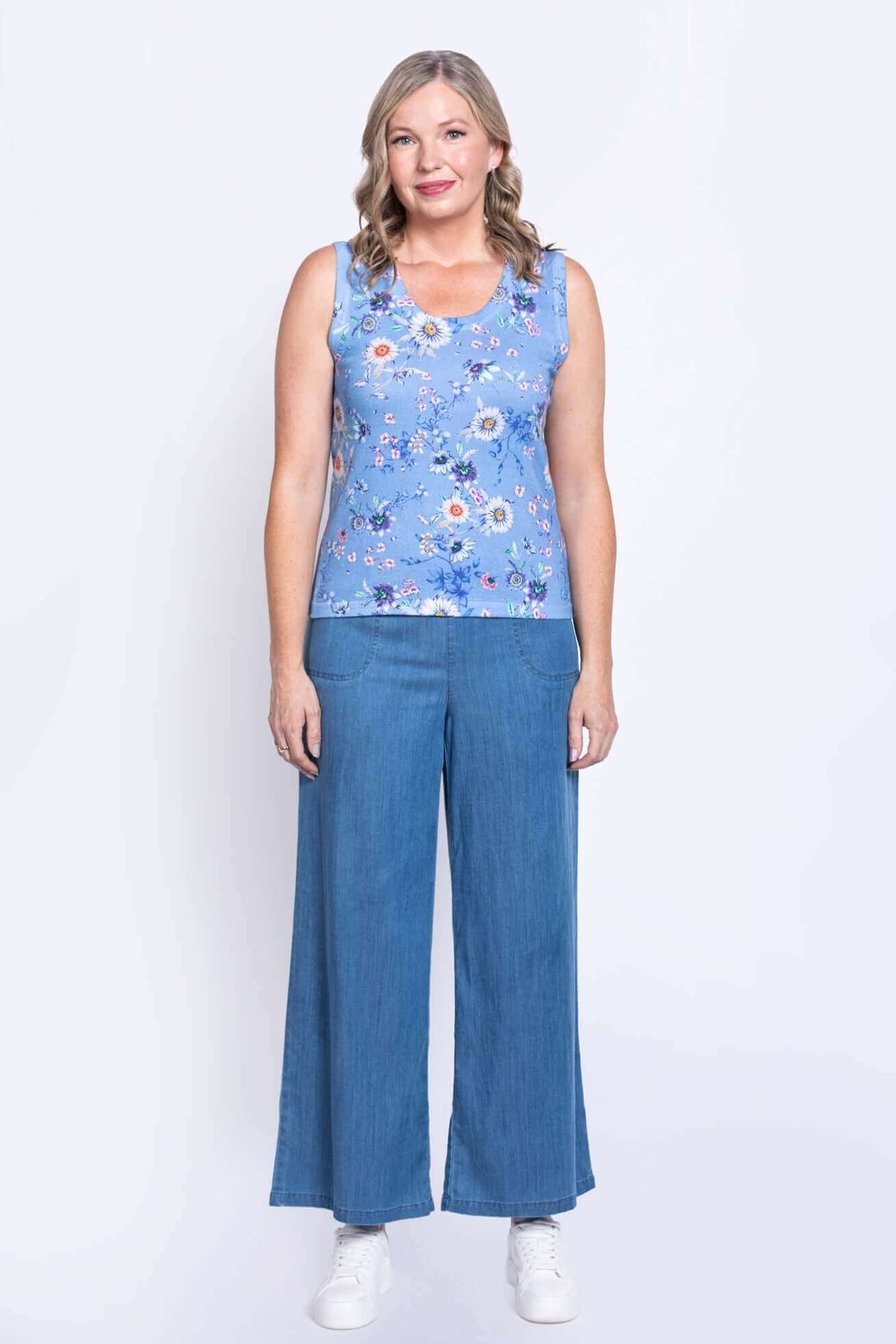 Full body view of woman in blue floral tank top and wide-leg denim pants