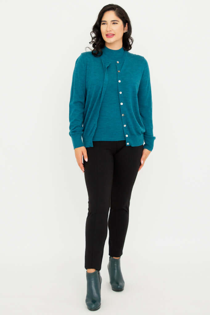 Full body view of woman modeling teal merino wool sweater set with black pants