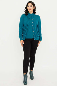 Full body view of woman modeling teal merino wool sweater set with black pants