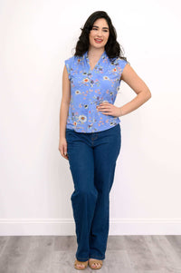 Full body view of a woman in a blue floral sleeveless top and wide-leg jeans