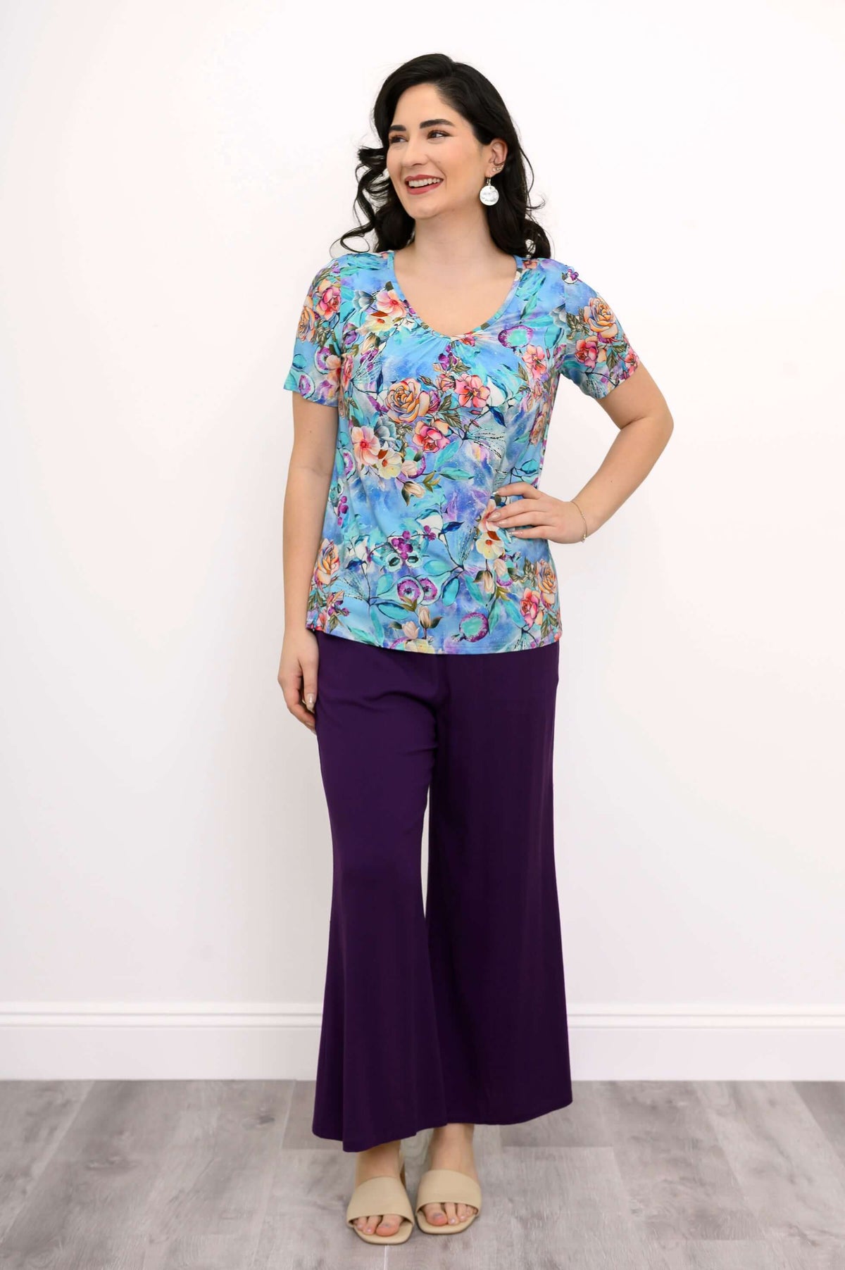 Full body view of a woman in a blue floral bamboo top and purple pants