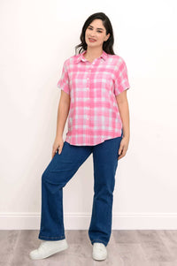 Full body view of a woman in a pink plaid blouse, blue jeans, and white sneakers