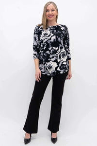 Full body view of a woman modeling a black and white floral pullover sweater with black pants