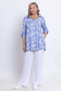 Full body view of woman in blue paisley tunic and white wide-leg pants