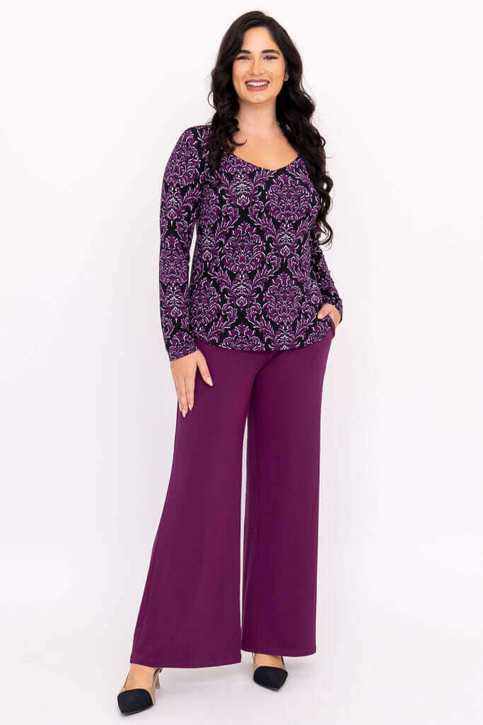 Woman smiling in full outfit with purple damask print top and purple pants