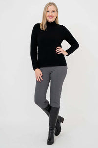 Full body view of woman in black mock neck sweater, grey pants, and black boots