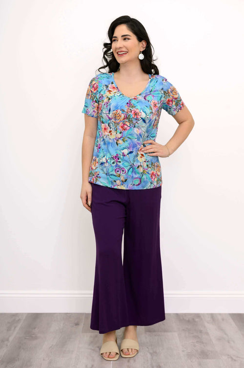 Full body view of woman in blue floral bamboo top and purple pants
