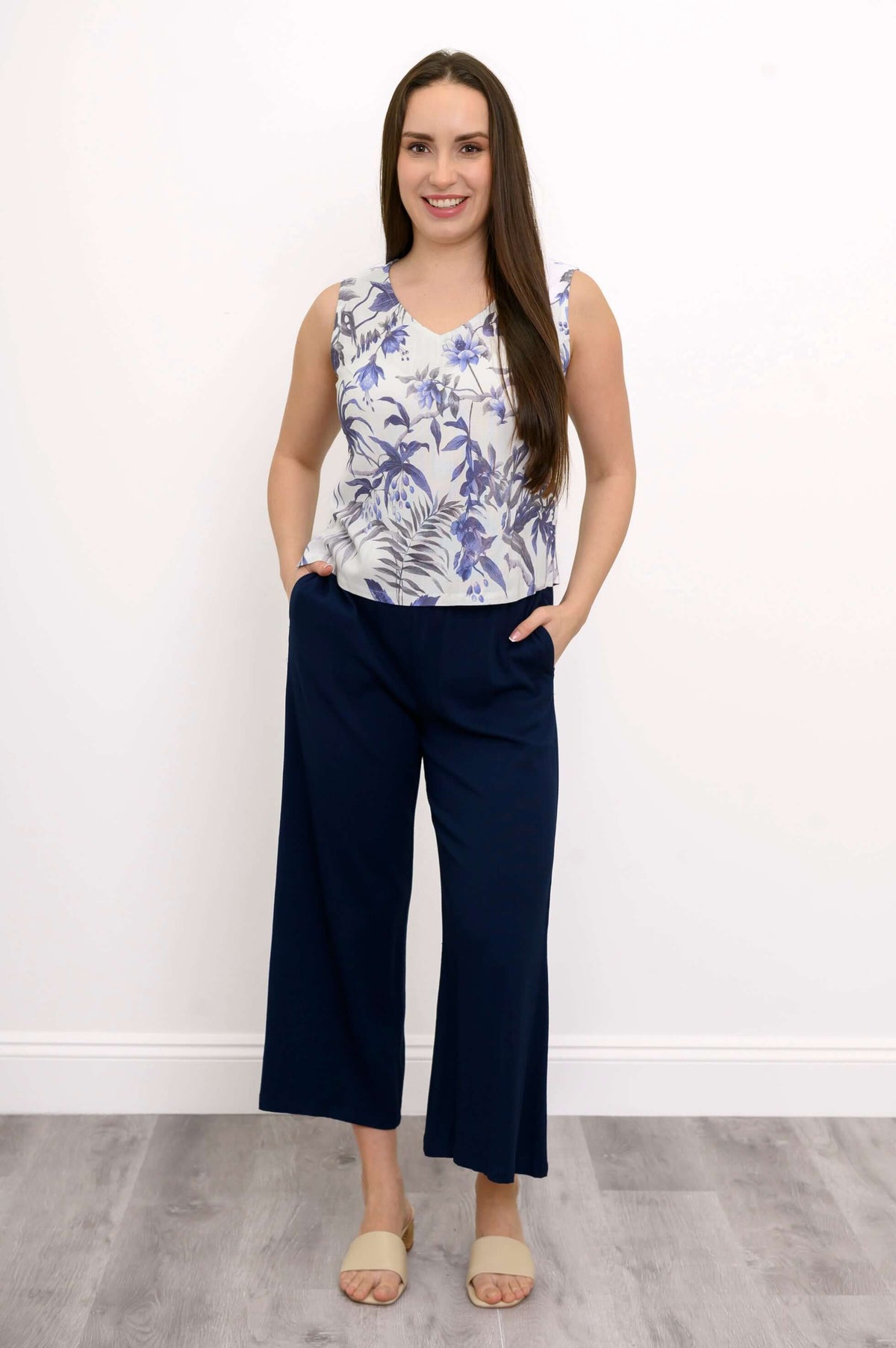 Full body view of a woman in a floral V-neck cropped tank and navy wide-leg pants