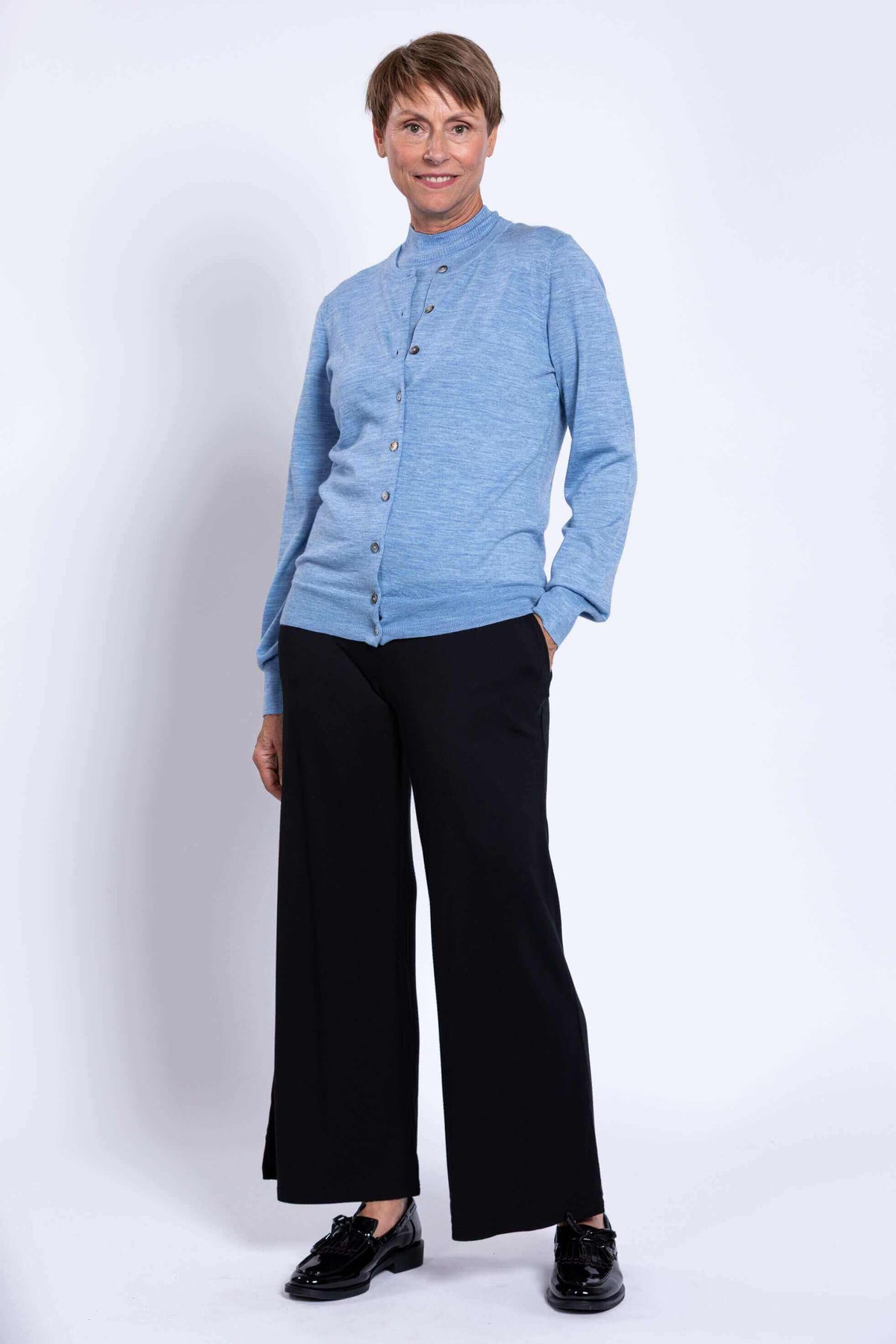Full body view, woman modeling light blue button-up cardigan with black pants
