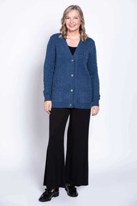 Full body view of woman in blue cable knit cardigan and black pants