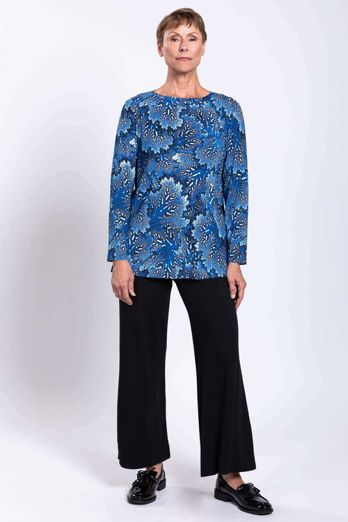 Full body view of woman in blue coral print top and black pants