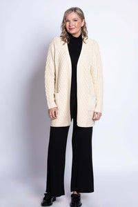 Full body shot of a woman in a cream cable knit open front cardigan with black outfit