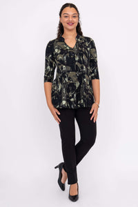 Full body view of woman modeling a black and green abstract print pullover top and black pants