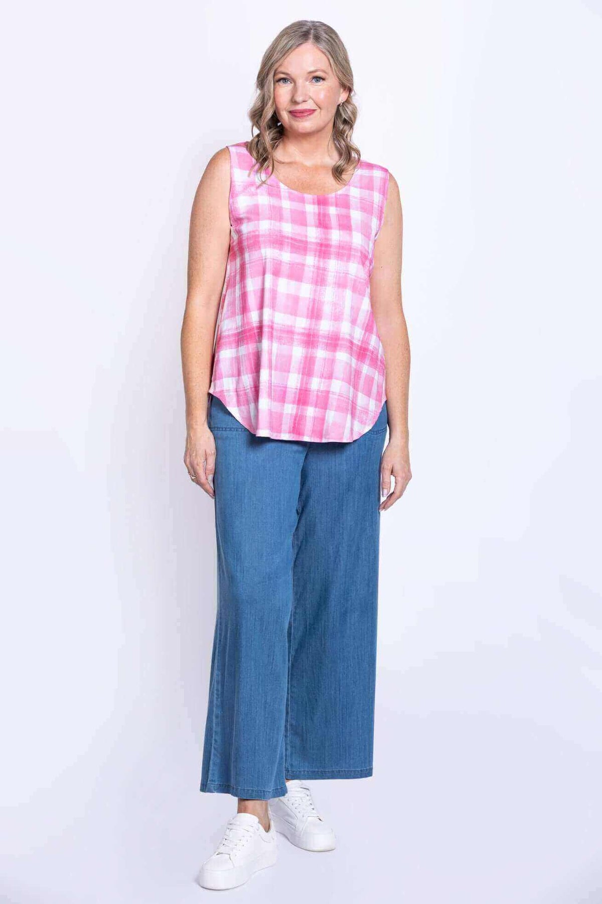 Full body view of woman in pink plaid sleeveless tank and blue wide-leg jeans