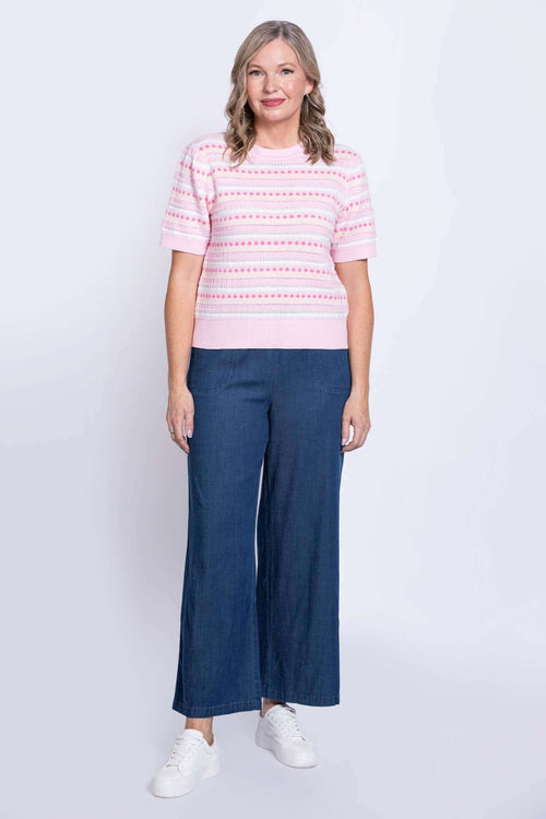 Full body view of woman in pink sweater and wide-leg blue pants
