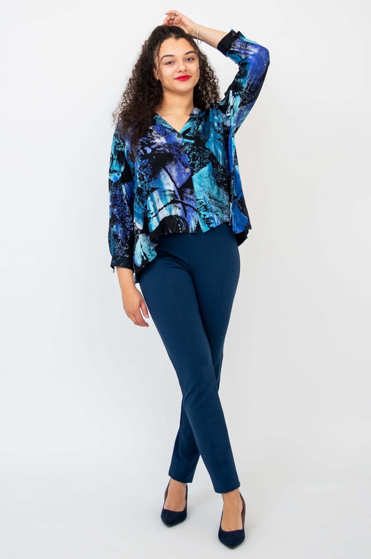 Woman standing and posing in blue abstract print hi-lo cropped blouse and navy pants