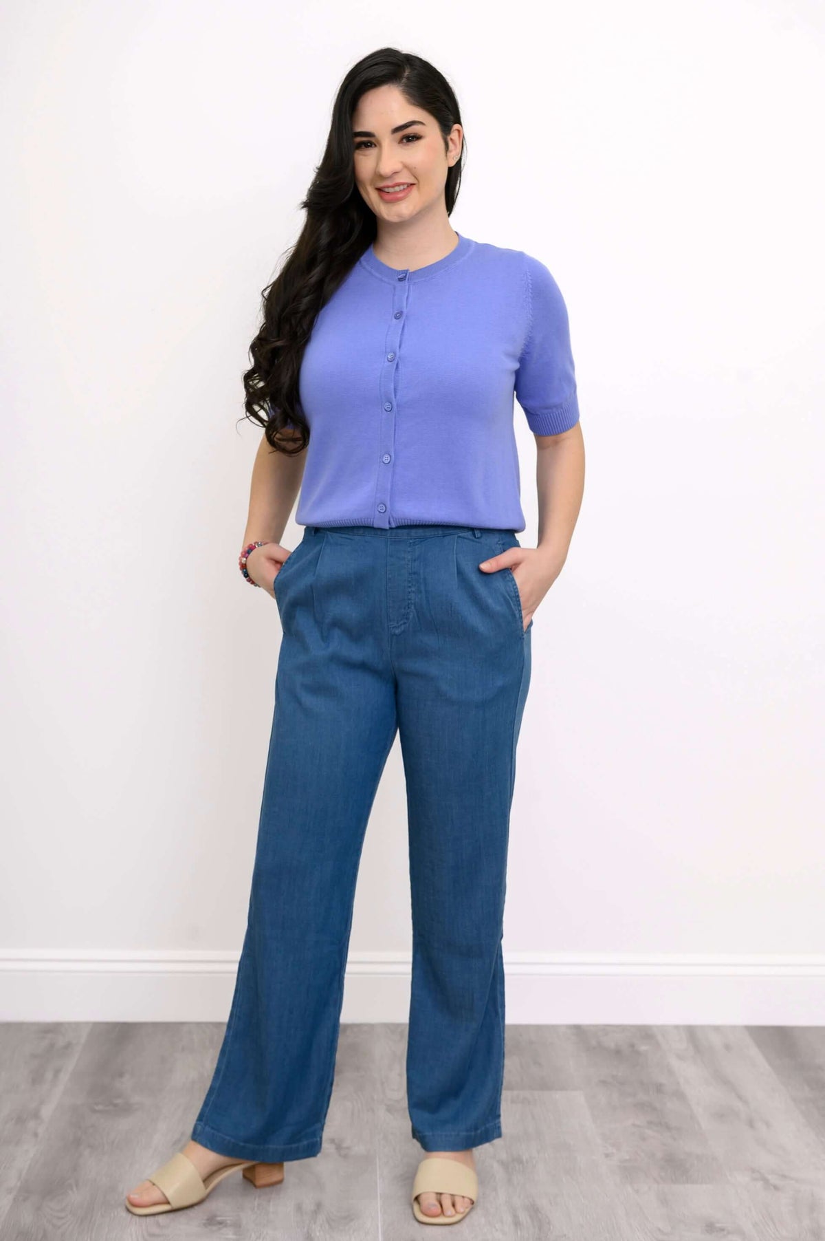 Woman in full view wearing a lavender short-sleeve cardigan and blue pants