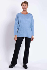 Full body straight front view of woman in light blue sweater and black pants
