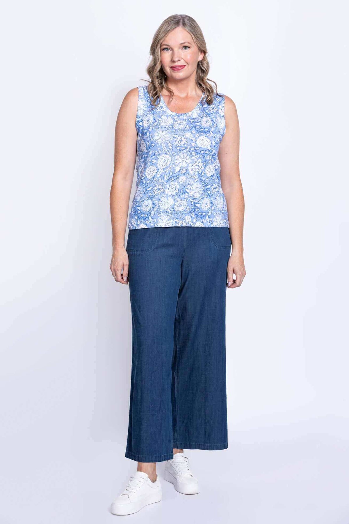 Full body front view of woman in blue floral tank top with wide-leg pants