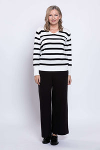 Full body view of woman in black and tan striped V-neck sweater and black pants