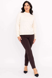 Full body shot of a model showcasing an ivory mock neck knit pullover top styled with dark pants.