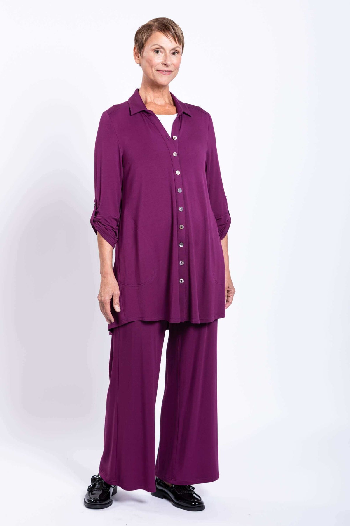 Full body view of a woman in a purple button-up bamboo tunic and matching wide pants