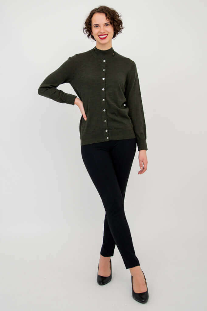 Woman models olive-green button-up sweater with black slim pants and heels, standing full body